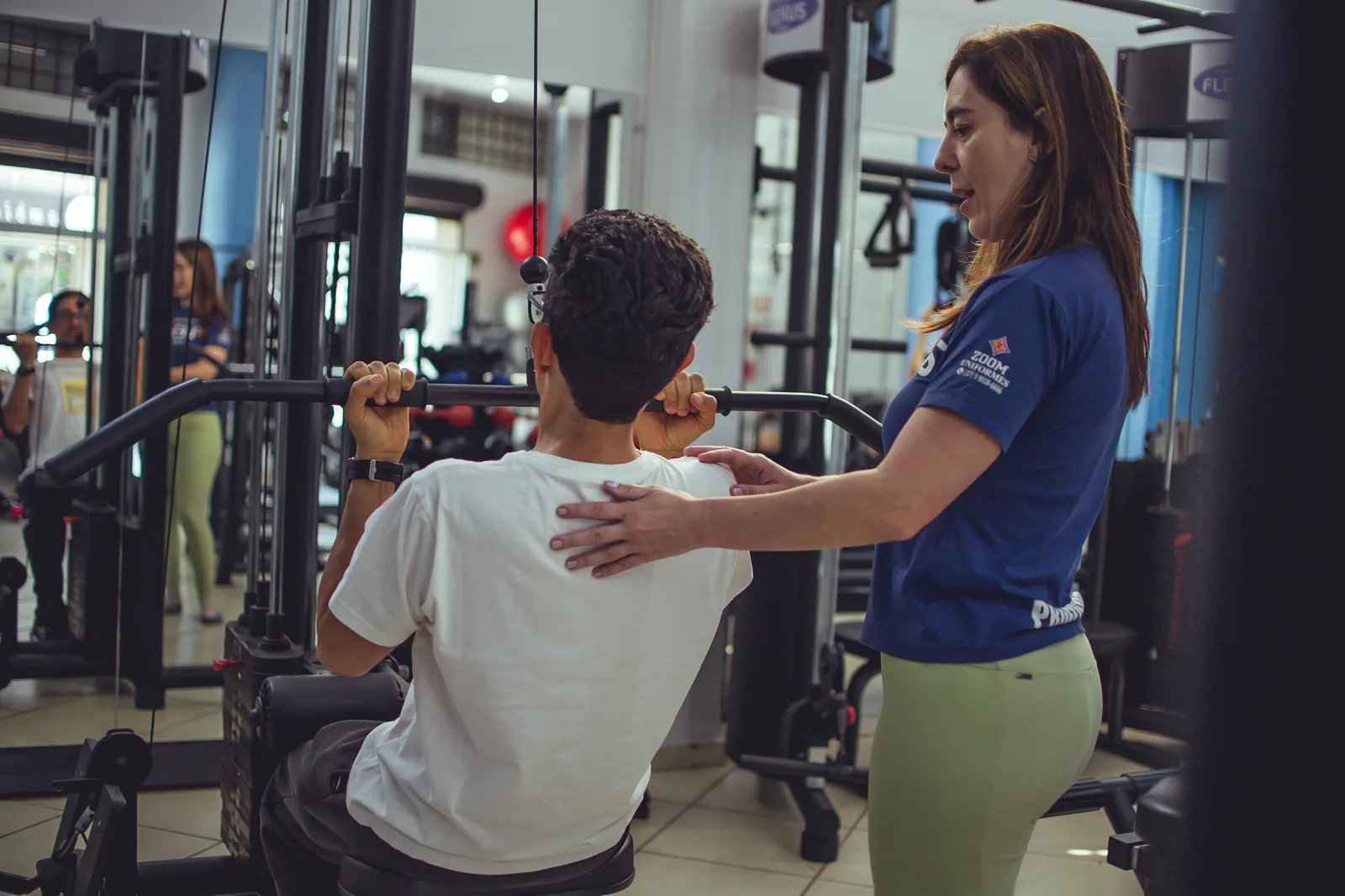 Profissional orienta a postura de aluno durante a musculação